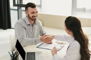 Man in an office shaking a woman's hand over life insurance in Lake Elsinore