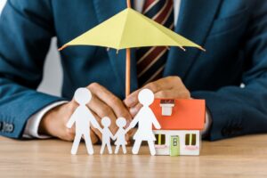 Man Holding an insurance umbrella over a paper family in Menifee